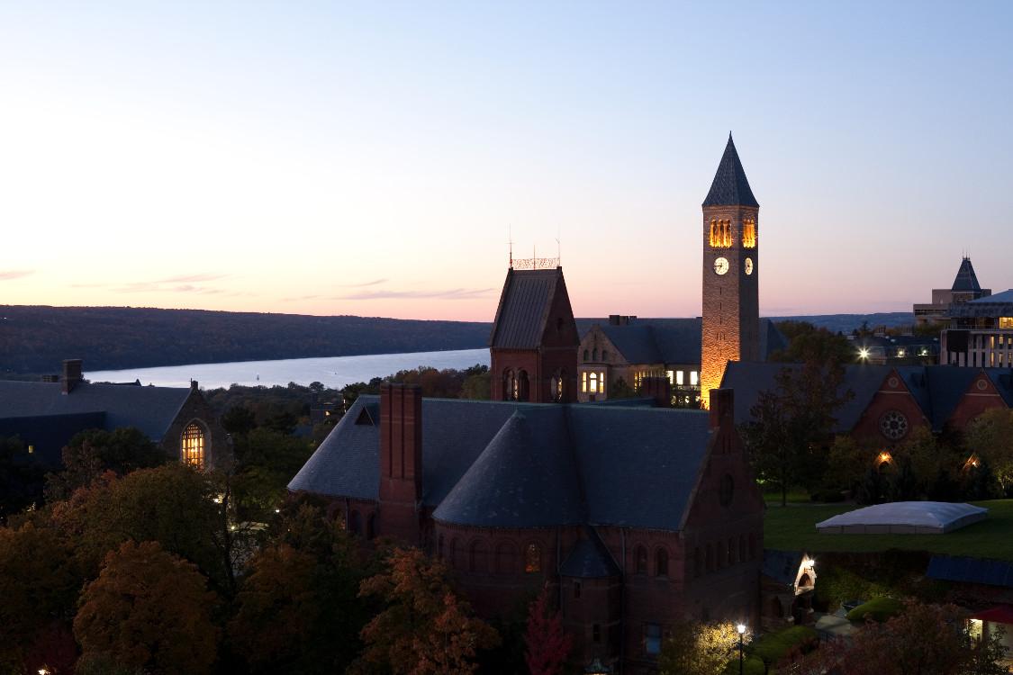 Clock tower at Cornell and campus buildings at dusk.